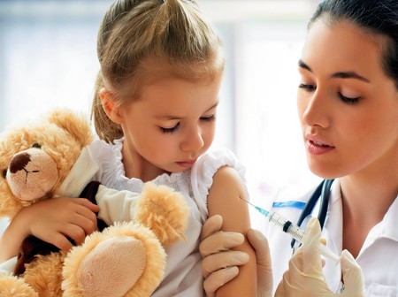 Enfermera con vacuna y niña